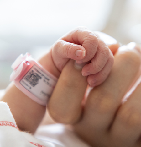 Infant holding mothers finger