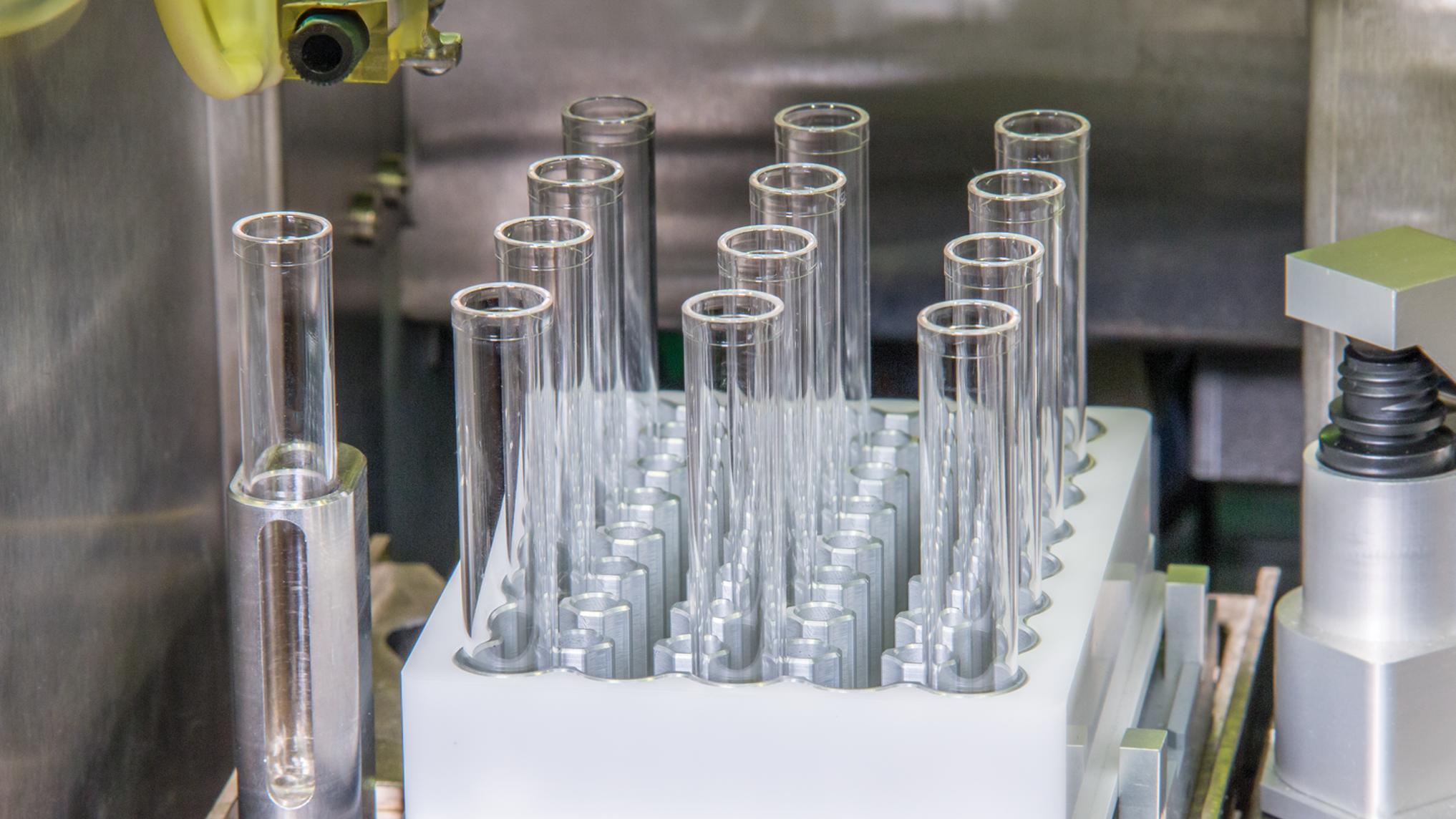 A set of empty glass test tubes neatly arranged in a white holder on laboratory equipment